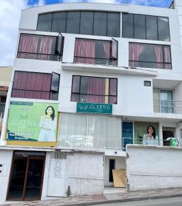 a white building with windows and signs on it at Habitaciones Alkimya in Loja