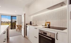 a white kitchen with a sink and a counter top at Waihi Beach Oasis - Apartment B1 in Waihi Beach