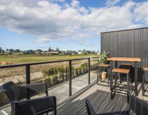 a deck with chairs and tables and a view of a field at Waihi Beach Oasis - Apartment B1 in Waihi Beach