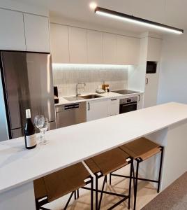 a kitchen with a counter with two glasses of wine at Waihi Beach Oasis - Apartment B1 in Waihi Beach