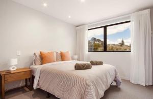 a white bedroom with a bed and a window at Waihi Beach Oasis - Apartment B1 in Waihi Beach +17 photos
