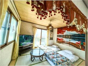 a room with two beds and a tv and a table at 温泉郡宿 in Toon