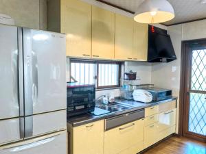 a kitchen with a refrigerator and a sink in it at 温泉郡宿 in Toon
