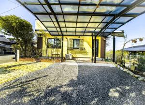 an open pergola over a driveway in front of a house at 温泉郡宿 in Toon