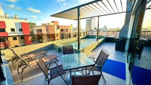 a patio with a table and chairs on a roof at Flat com acesso rápido as praias e o melhor do turismo local in João Pessoa