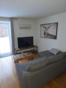 a living room with a couch and a deer on the wall at Loft La Pause Orford in Magog-Orford