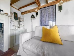 a couch with a yellow pillow on it in a living room at Prospect Cottage in Wittersham