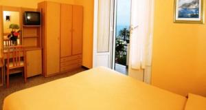Habitación amarilla con cama y ventana en Hotel Villa Bianca, en Laigueglia