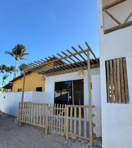 a building with a wooden gate and a wooden pergola at Casa aconchego do pontal in Fortim