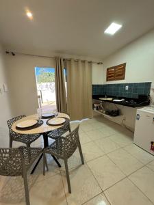 a dining room with a table and chairs and a kitchen at Casa aconchego do pontal in Fortim