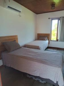 two beds in a bedroom with a window at Villa Chalés - andar superior in Barra Grande