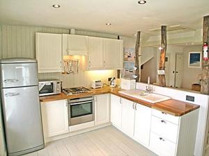a kitchen with white cabinets and a refrigerator at Kingsley Cottage in Instow