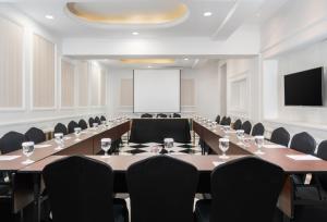 a boardroom with a long table and chairs and a screen at Swiss-Belexpress Palu in Palu