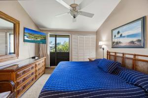 a bedroom with a blue bed and a ceiling fan at Spacious 2BR Oceanfront Loft - Unit C17 condo in Lahaina