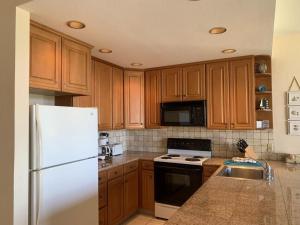 a kitchen with wooden cabinets and a white refrigerator at Napili Point Oceanfront Turtle View 1BR - Unit B30 condo in Lahaina
