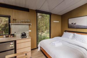 a bedroom with a bed and a desk and a window at Te Paki Dam View X by Tiny Away in Sanson