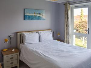 a bedroom with a white bed and a window at Alula Lodge in Lowestoft