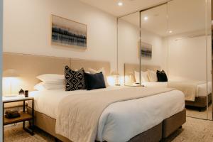 a bedroom with two beds and a large mirror at Punthill Williamstown in Williamstown +54 photos