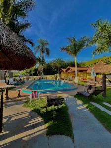 a swimming pool with benches and palm trees at Pousada Pé da Serra in Lindóia +85 photos