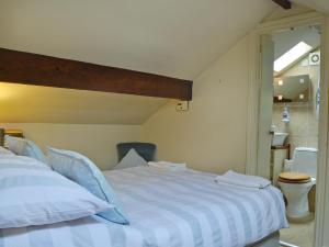 a bedroom with a blue and white bed and a toilet at The Pigsty Cottage E2783 in Oswestry +7 photos