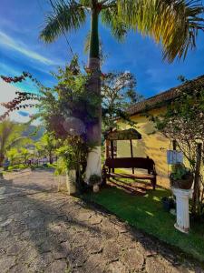 a house with a palm tree and a bench at Pousada Pé da Serra in Lindóia