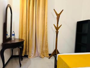 a bedroom with a yellow curtain and a table and a television at KOKO Villa in Kochchikade
