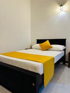 a bedroom with a bed with a yellow blanket on it at KOKO Villa in Kochchikade