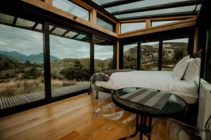 a bedroom with a bed and a table in front of windows at Manakau PurePod in Kaikoura