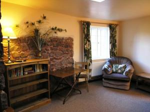 a living room with a table and a chair and a brick wall at West Wing- Ukc4914 in Timberscombe