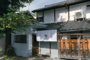 a white house with a wooden fence and a fan at 帰々Kiki in Yamatokoriyama