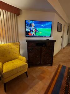 a living room with a television and a yellow chair at La Paloma in Rosarito Beach