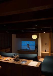 a room with a table and a tv in the background at 帰々Kiki in Yamatokoriyama