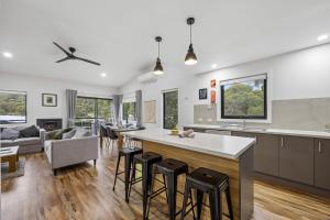 a kitchen and living room with a large island with bar stools at Roses Creek Chalet B in Crackenback