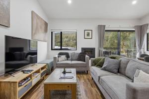 a living room with a couch and a table at Roses Creek Chalet B in Crackenback