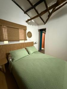 a bedroom with a green bed and a window at Hostal Casablanca in San Gil