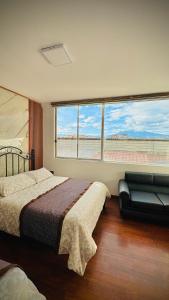 a bedroom with a bed and a couch and windows at Hotel El Altar in Riobamba