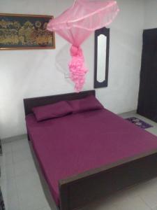 a bed with purple sheets and a pink dress on it at chula,s Home Stay in Matara