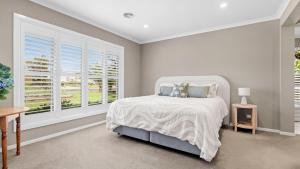 a white bedroom with a bed and a window at Secret Haven in Safety Beach +19 photos