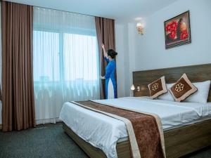 a woman is looking out the window of a hotel room at Nhà khách Bông Sen in Vinh