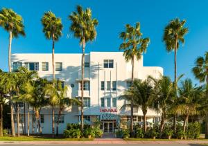 a white building with palm trees in front of it at Hotel Trouvail Miami Beach in Miami Beach