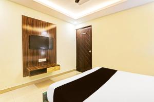 a bedroom with a bed and a tv and a door at Super Hotel O Kathauta Jheel Malhaur Gomti Nagar in Lucknow
