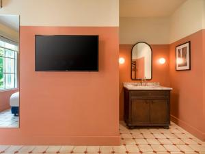 a bathroom with a flat screen tv on a wall at Hotel Trouvail Miami Beach in Miami Beach