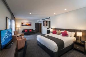 a bedroom with a large bed and a living room at Alexandra Hills Hotel in Cleveland