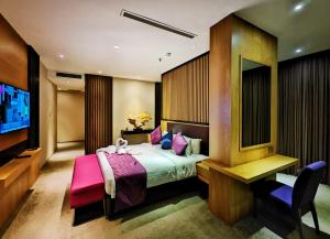 a bedroom with a bed and a flat screen tv at Greens Hotel & Suites in Bintulu