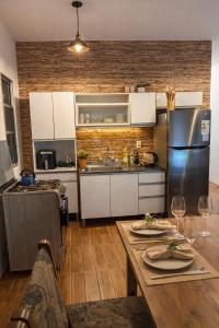 a kitchen with white cabinets and a stainless steel refrigerator at Refugio del bosque - Casa con jacuzzi descanso en Piriapolis in Piriápolis