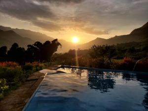 a swimming pool with the sunset in the background at My's Hmong House in Tả Van