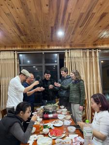 a group of people standing around a table with food at My's Hmong House in Tả Van