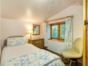 a bedroom with a bed and a chair and a window at Bilbrook- Ukc4913 in Timberscombe