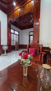 a room with a couch and a vase with flowers on a table at Rose House - Quảng Bình in Bố Trạch +21 photos