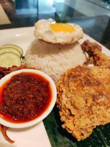 a plate of food with rice and an egg and sauce at Greens Hotel & Suites in Bintulu
